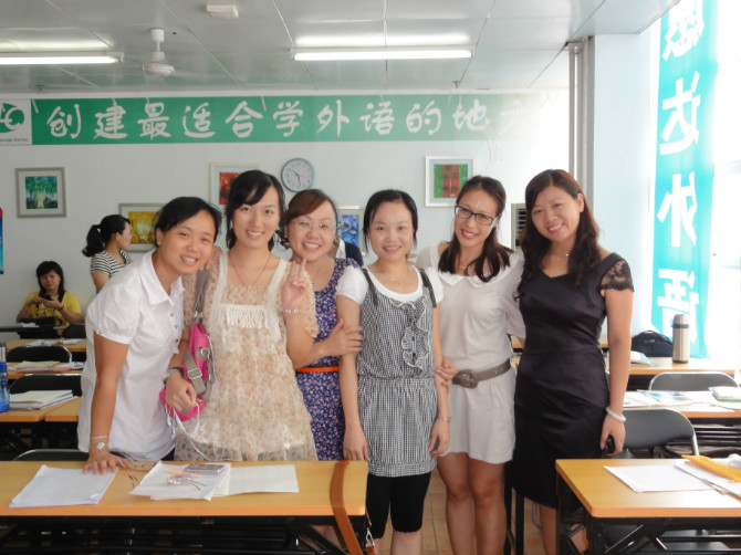 A small group posing together among desks in a language classroom.