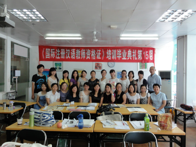 A class group posing beneath a Chinese-language teacher-training graduation banner.